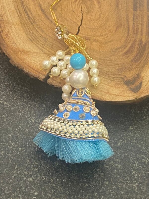 Handcrafted Blue Pearl Bhabhi Rakhi (ब्लू पर्ल भाभी राखी) with blue fabric, white beads resembling pearls, and floral charm