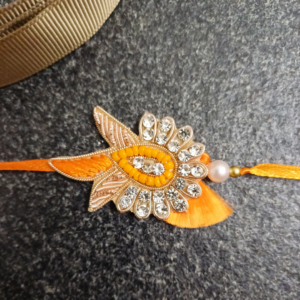 Orange Pearl Jardosi Rakhi featuring intricate Jardosi, Resham, and Chid work with a beautiful stone centerpiece and pearl bead