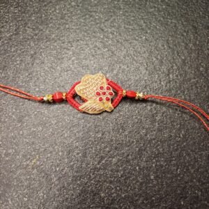 Crimson Petal Resham Rakhi with golden floral motif and red stones on a red thread