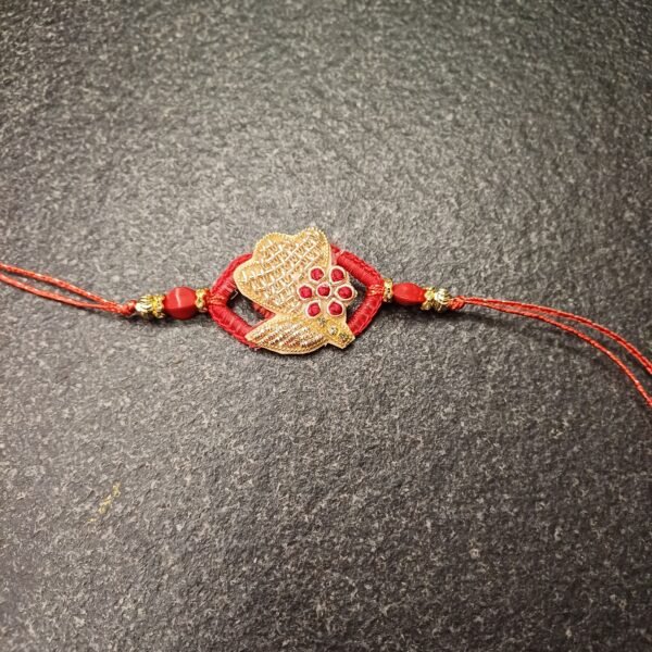 Crimson Petal Resham Rakhi with golden floral motif and red stones on a red thread