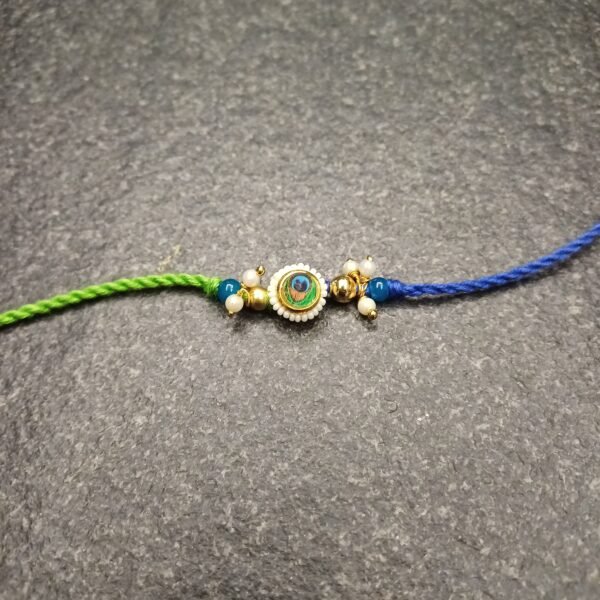 Peacock Charm Resham Rakhi with green-blue thread and peacock feather charm