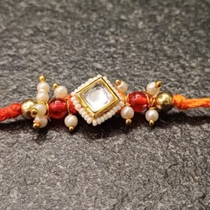 Square kundan rakhi with pearls and red beads on orange thread